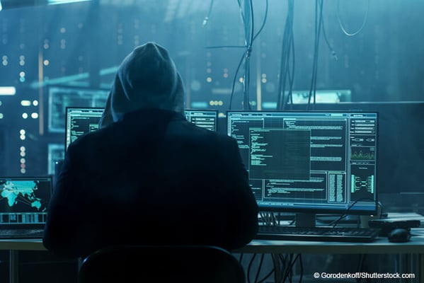 Hacker sitzt an mehreren Bildschirmen 