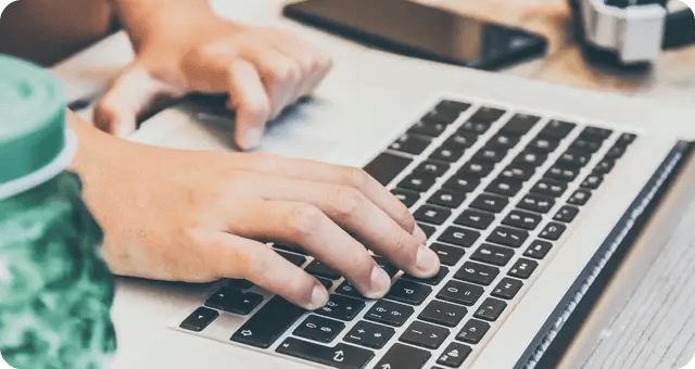 Hände tippen etwas auf einer Laptoptastatur