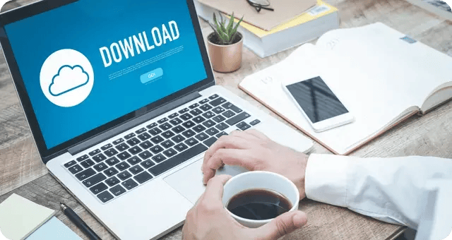 Mann mit Kaffee in der Hand lädt etwas an seinem Laptop herunter
